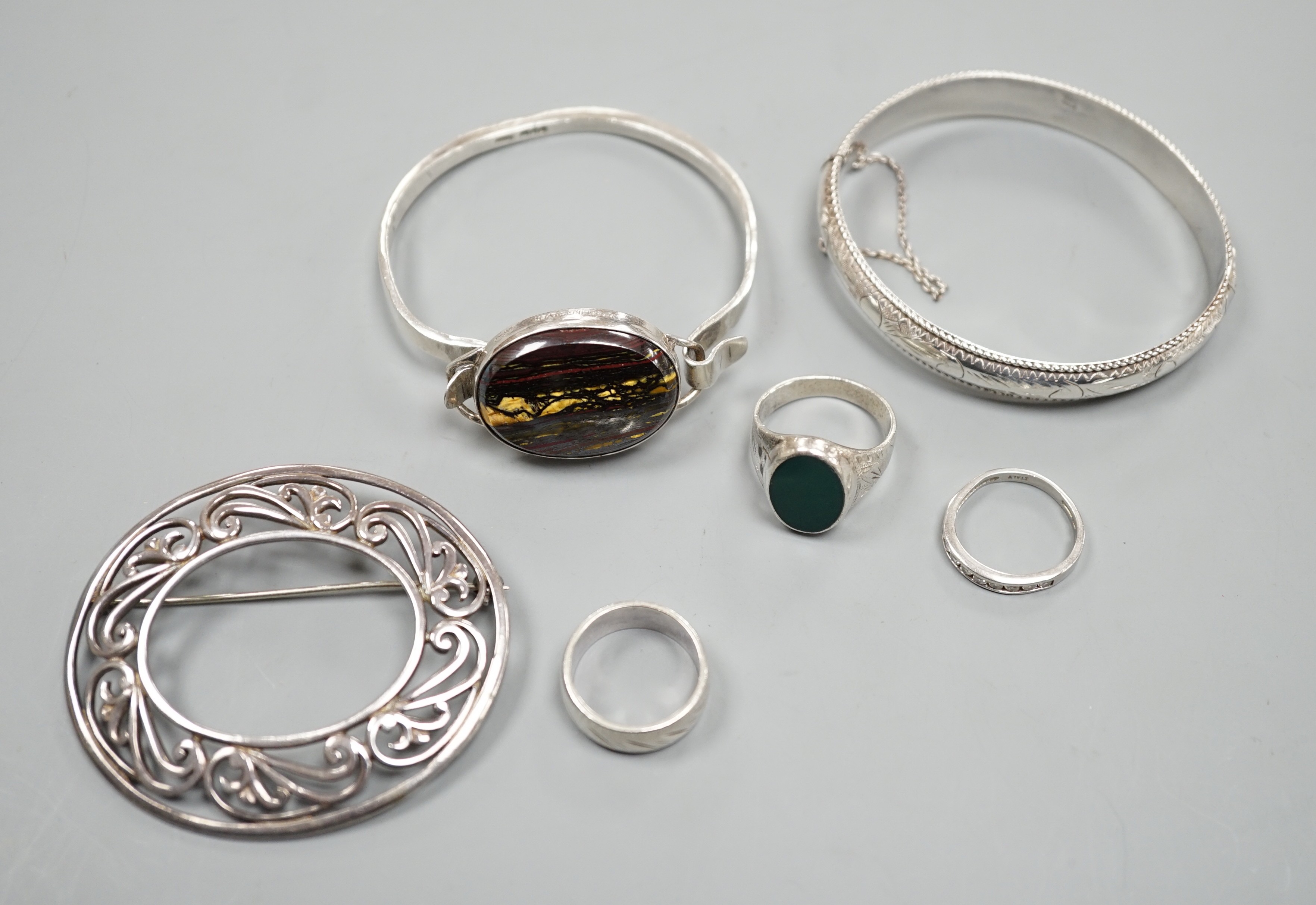 A 1970's silver and oval quartz set bangle, two other white metal bangles and three assorted rings.